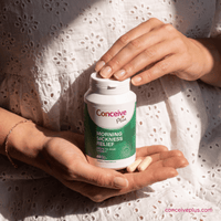 Person holding a bottle of Conceive Plus morning sickness relief supplement with pills in their hand.